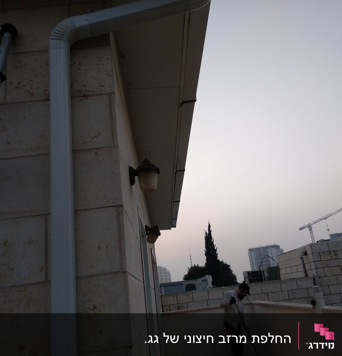 מרזב לבן מחובר לגג בניין אבן